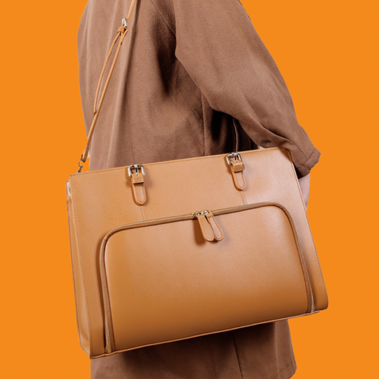 Brown leather handbag held by a person against an orange background