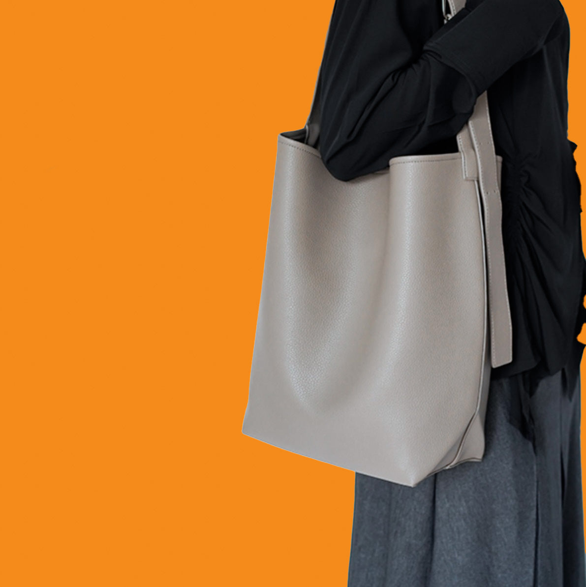 Person wearing a light gray tote bag against an orange background