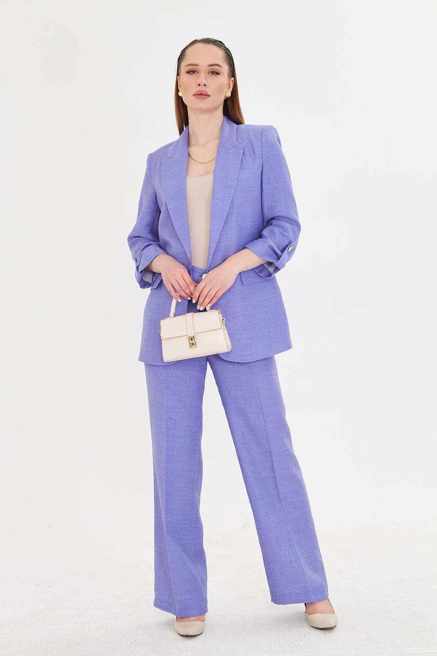 Woman wearing a light purple suit with a white handbag on a white background