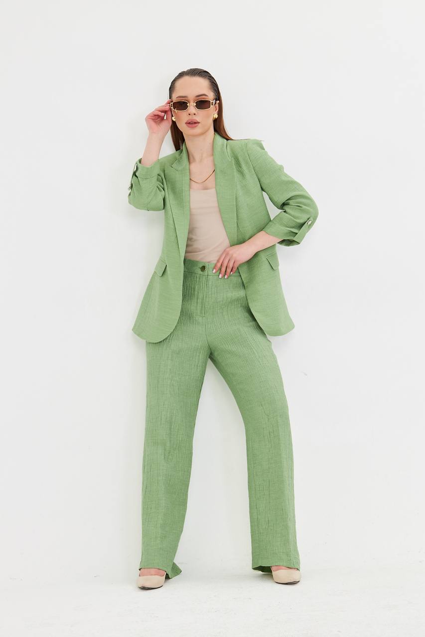 Woman wearing a green suit with sunglasses on a white background