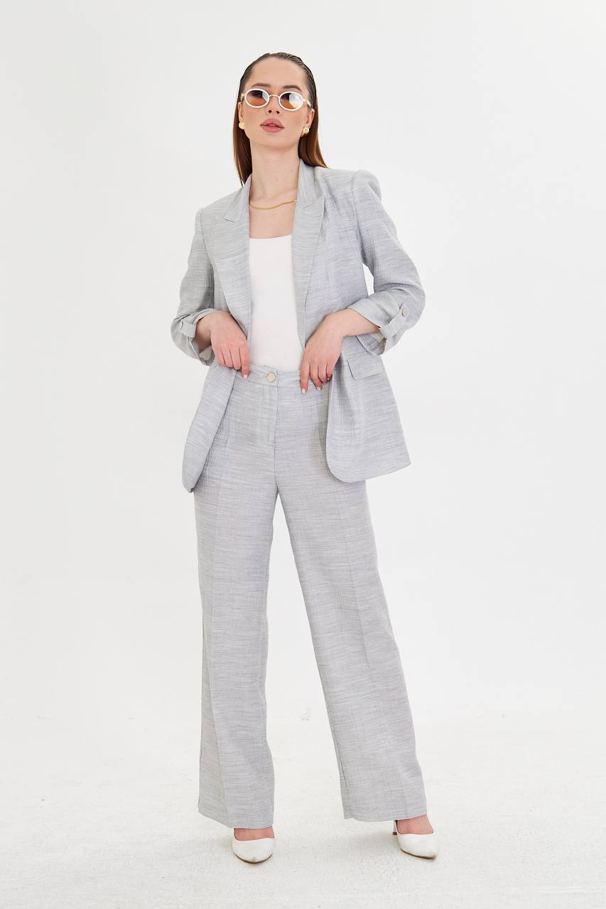 Woman wearing a light gray suit with a white top on a white background