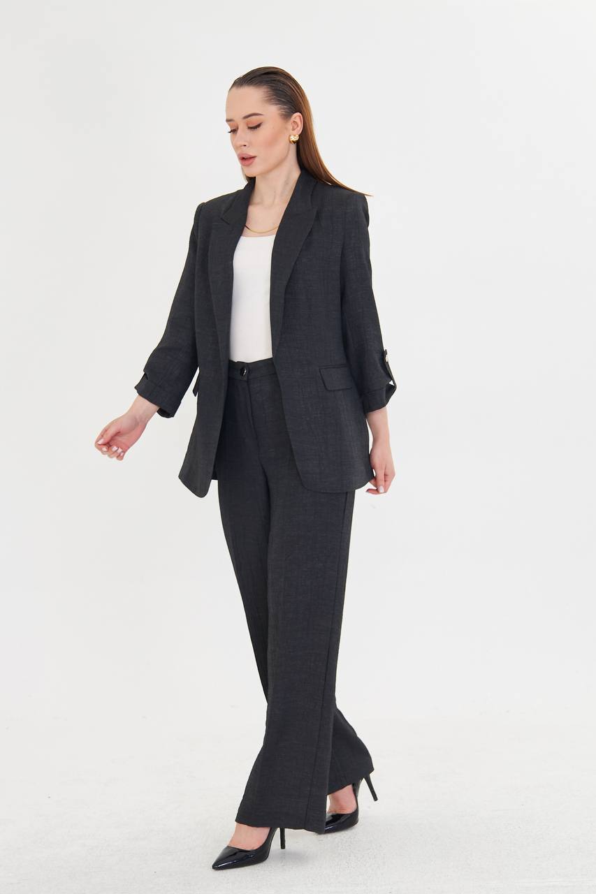 Woman wearing a dark gray suit with a white top on a white background
