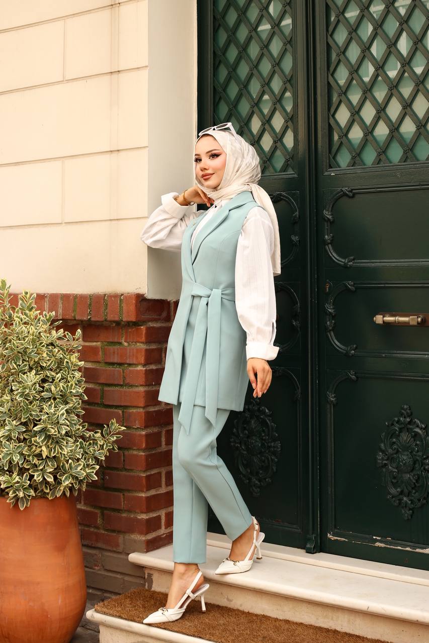 Woman in a light blue outfit standing outside a building with decorative doors.