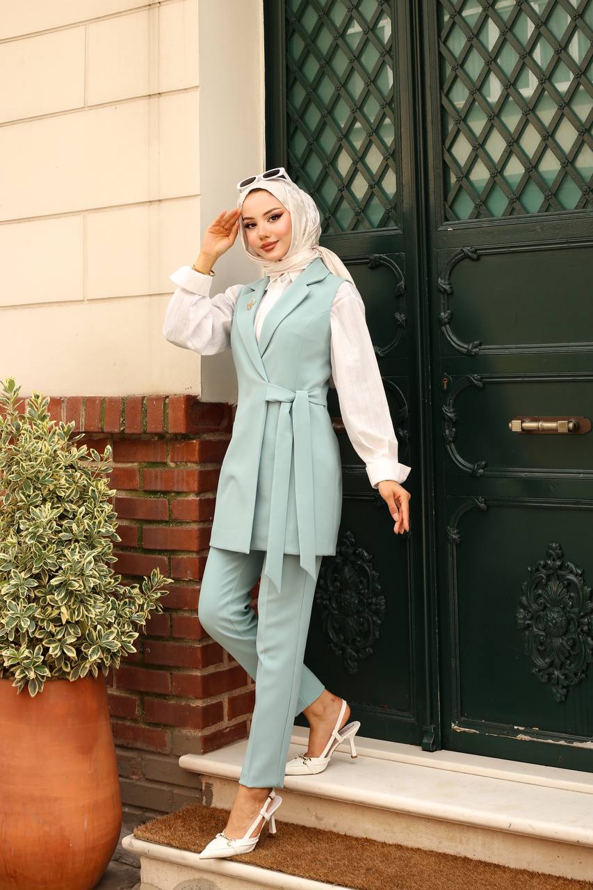 Woman in a light blue outfit standing outside a building with a green door.