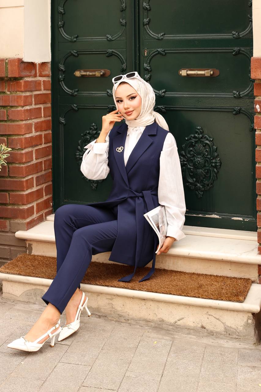 Woman in a navy blue outfit sitting on a step in front of a large green door.
