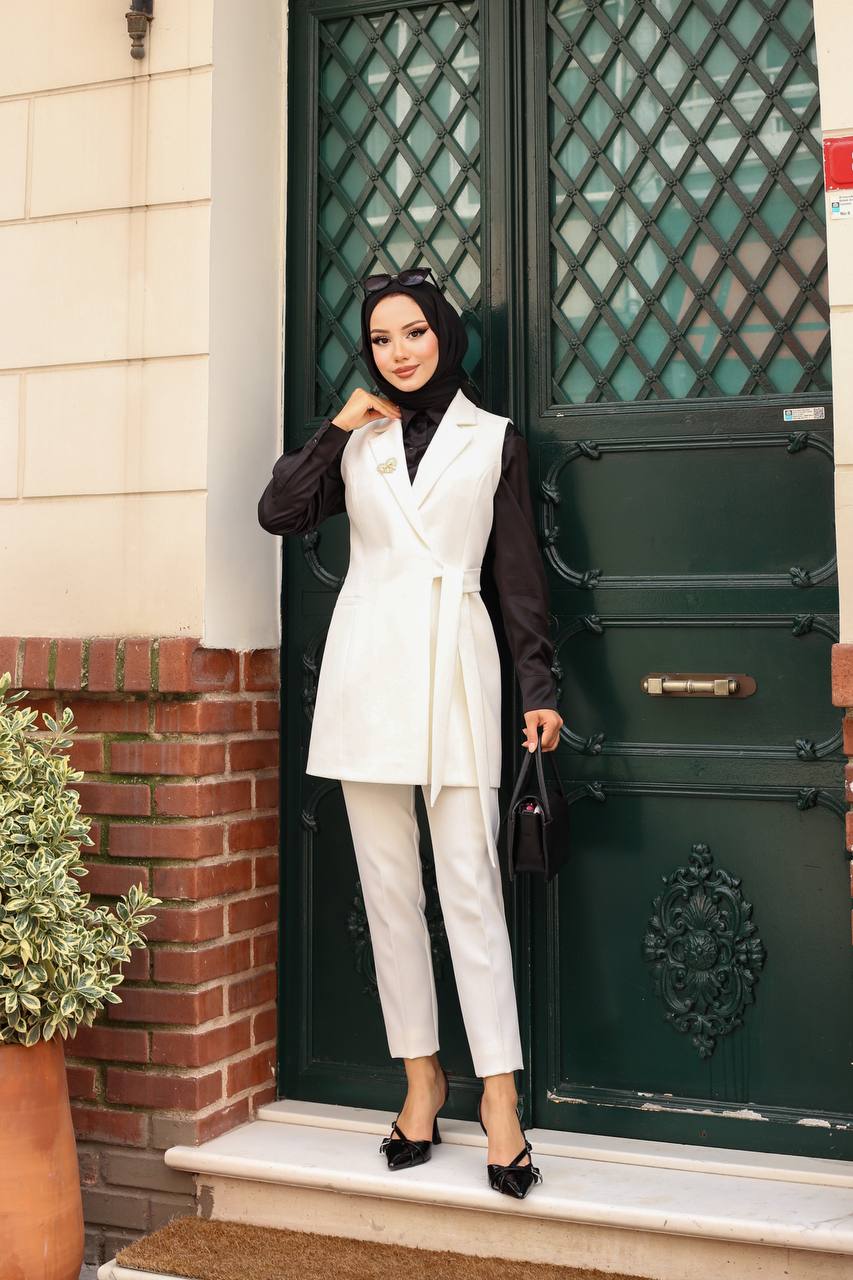 Woman in a white outfit standing in front of a green door.