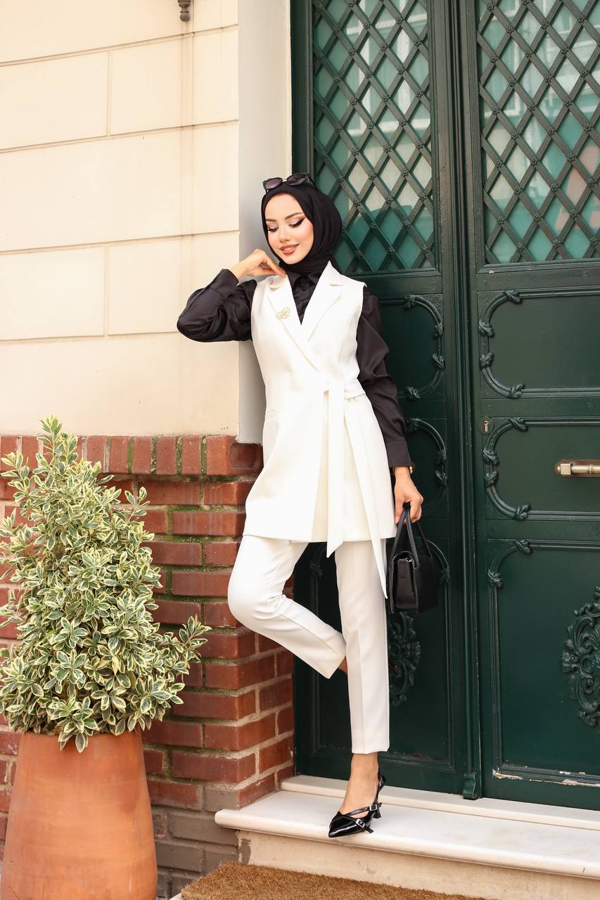 Woman in a white outfit standing outside a building with a green door.