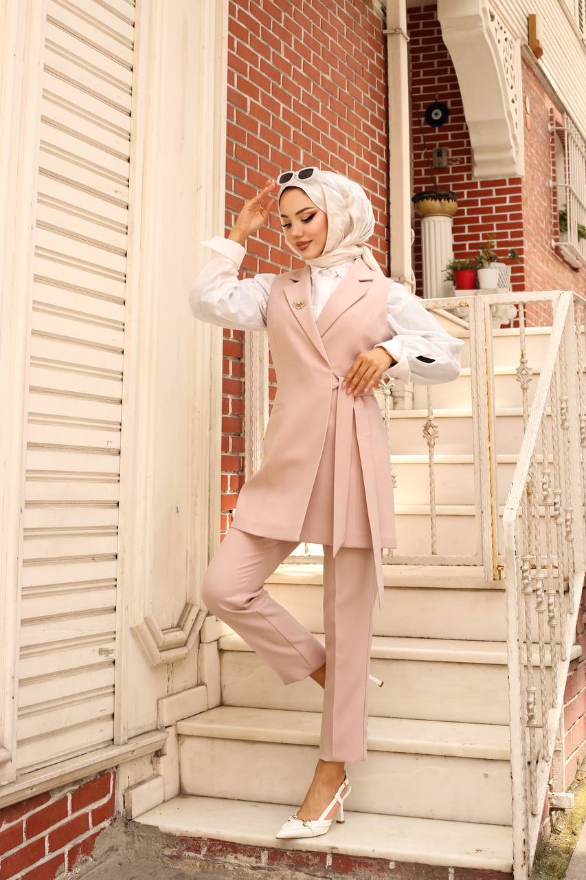 Woman in a pink outfit standing on steps with a brick wall background