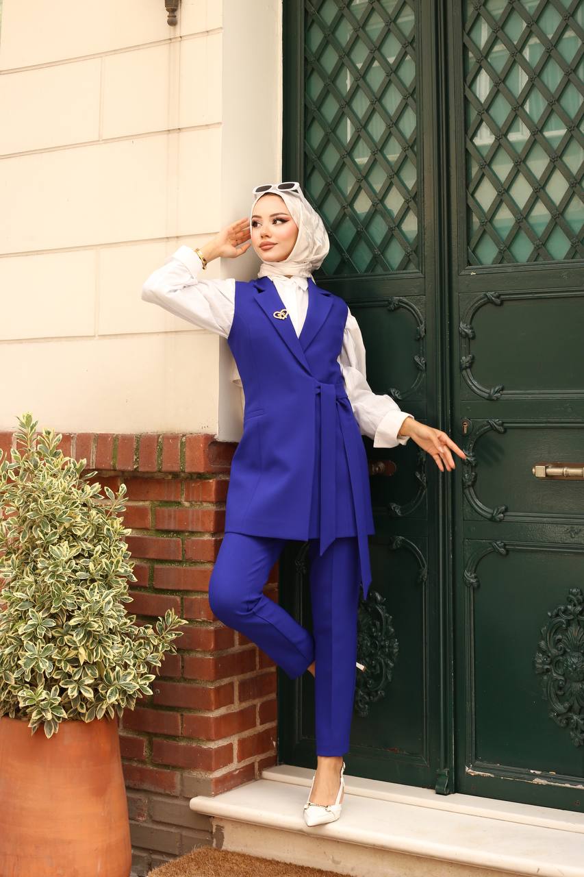Woman in a blue outfit standing in front of a green door.