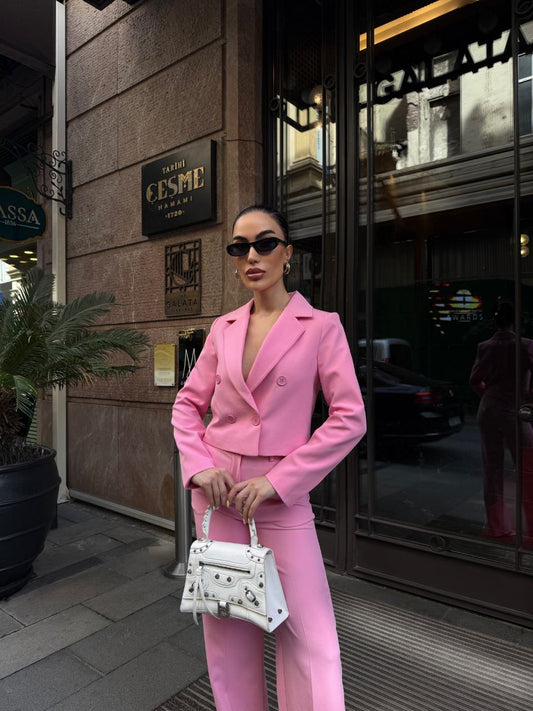 Woman in a pink suit standing in front of a building entrance.