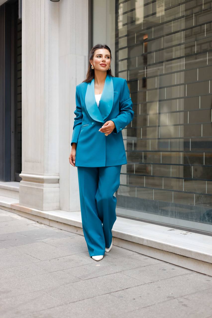 Woman in a blue suit walking on a city street.