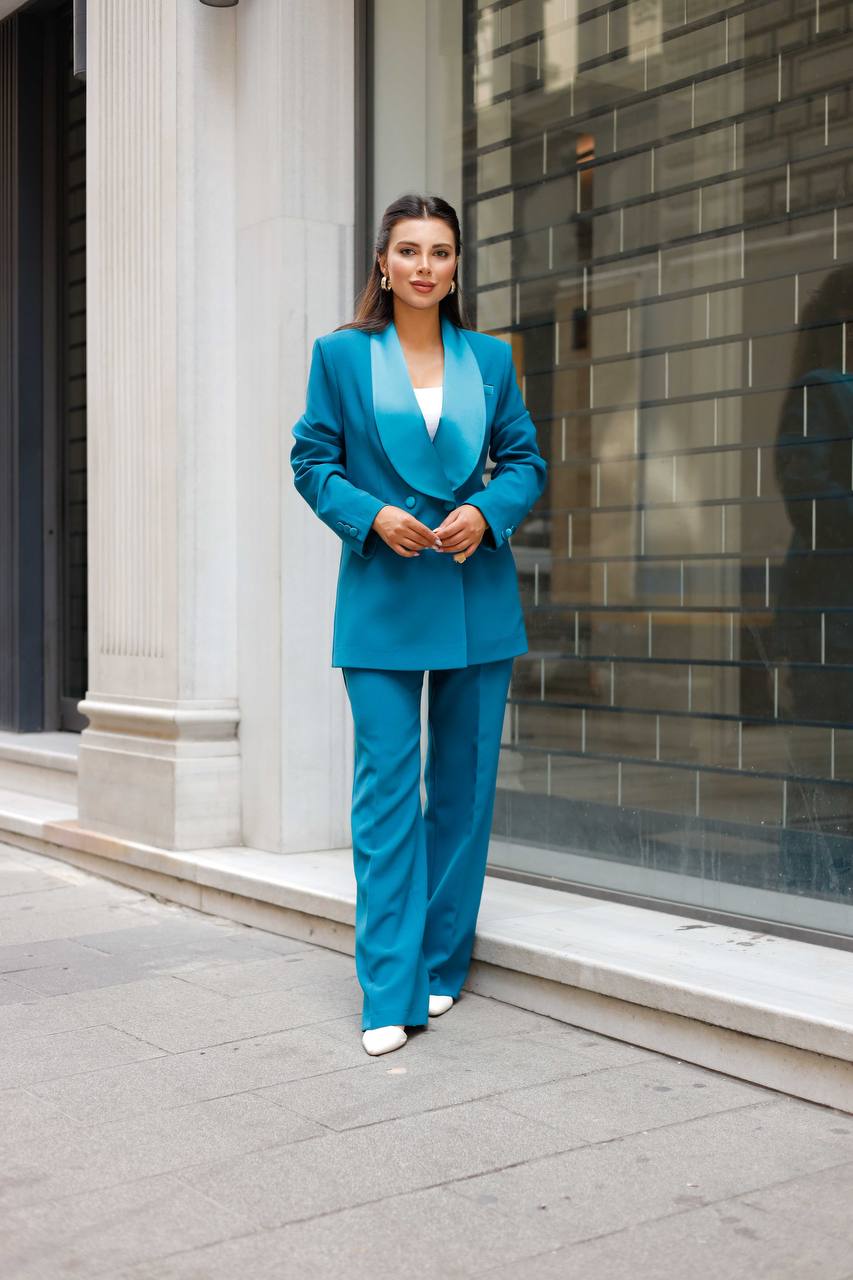 Woman in a blue suit standing on a city street.
