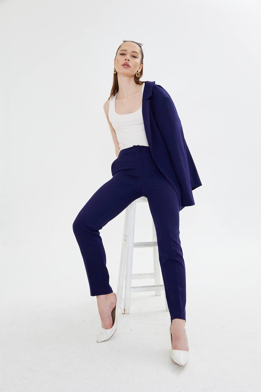 Woman wearing a navy blazer and pants with a white top on a white background