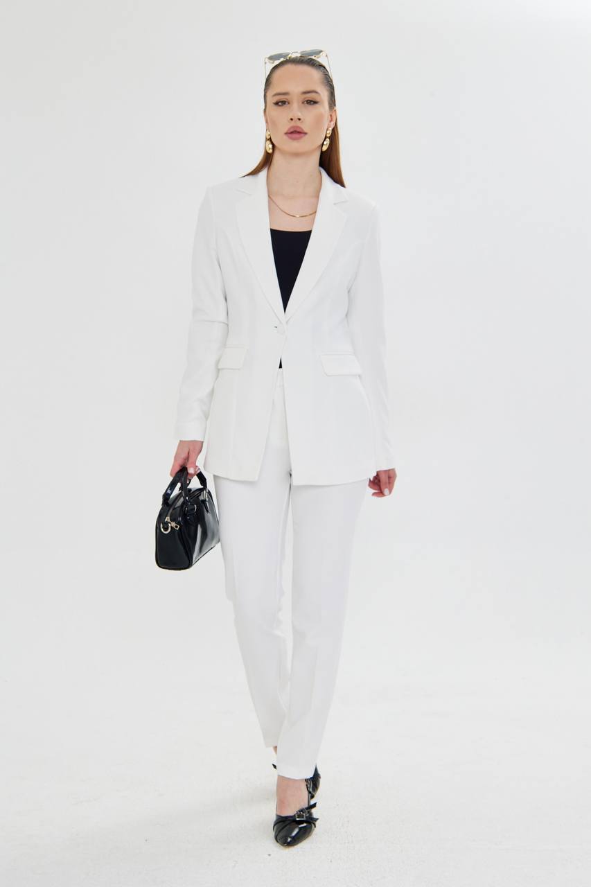 Woman wearing a white suit holding a black handbag on a white background