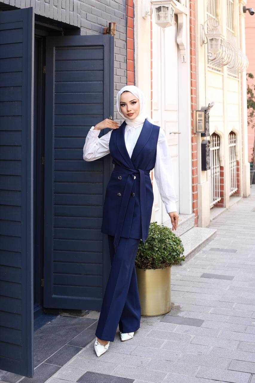 Woman in a navy blue suit standing next to a building entrance.