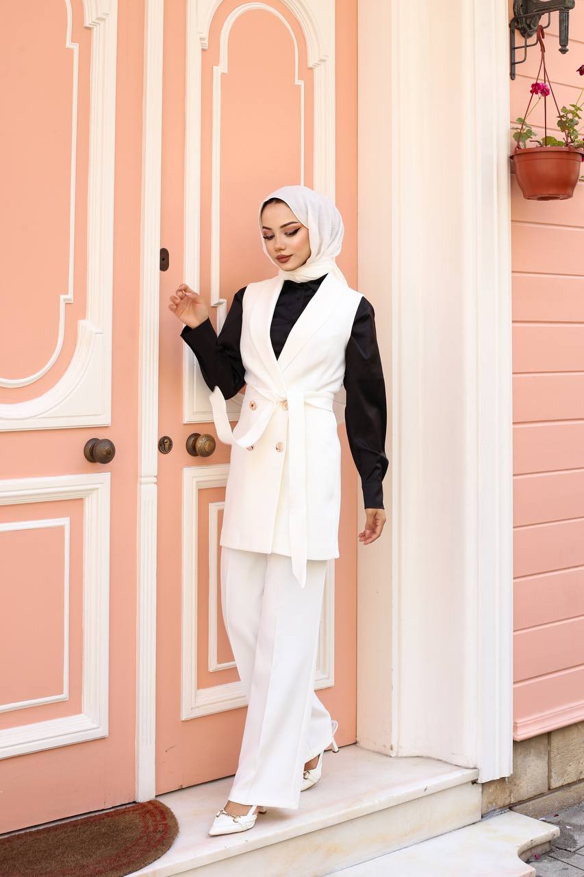 Woman in a white outfit standing in front of a pink door