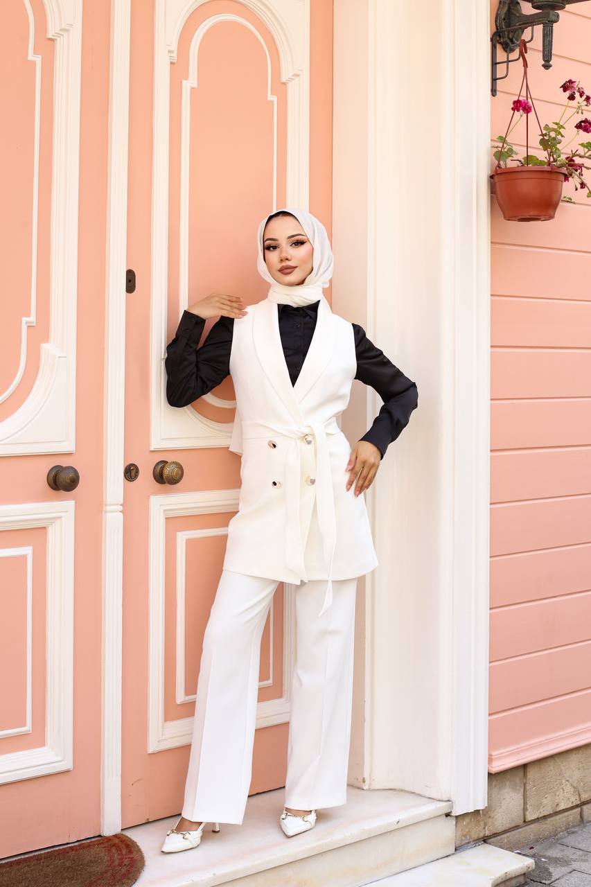 Woman in a white outfit standing in front of a pink door