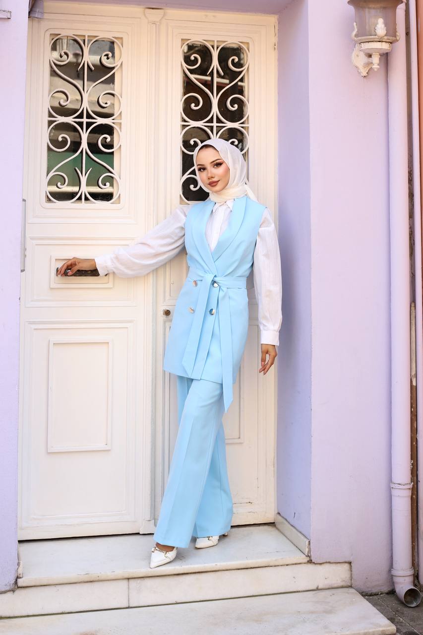 Woman in a light blue outfit standing in front of a white door with decorative glass panels.