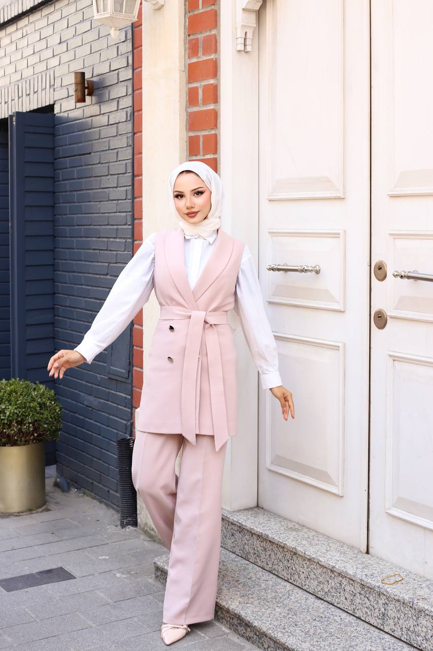 Woman in a pink outfit standing outside a building with a white door.