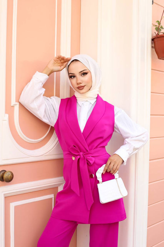 Woman wearing a bright pink outfit with a white top against a light pink wall.