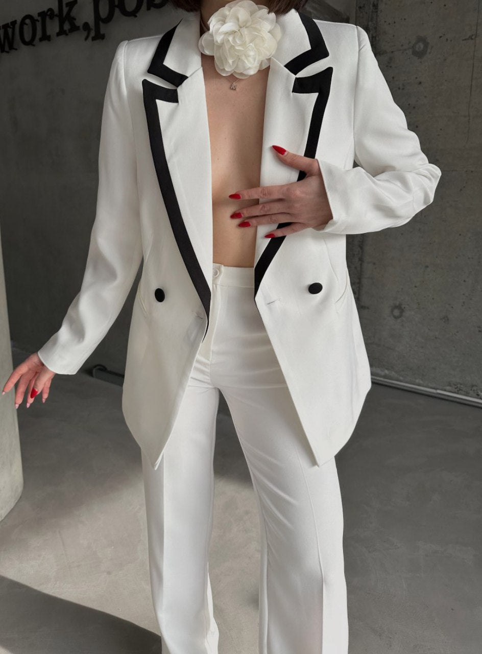 Person wearing a white suit with black accents in an urban setting