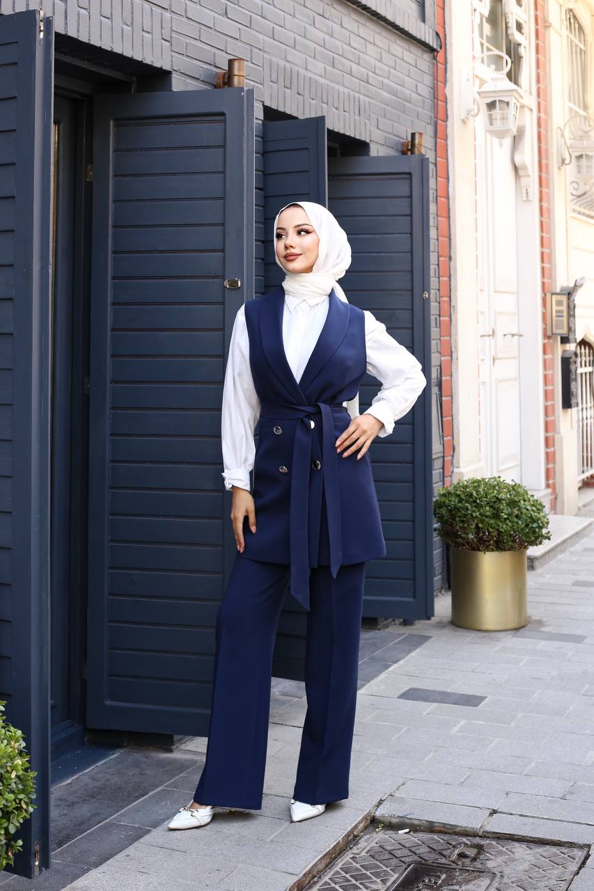 Woman in a blue outfit standing in front of a building entrance.