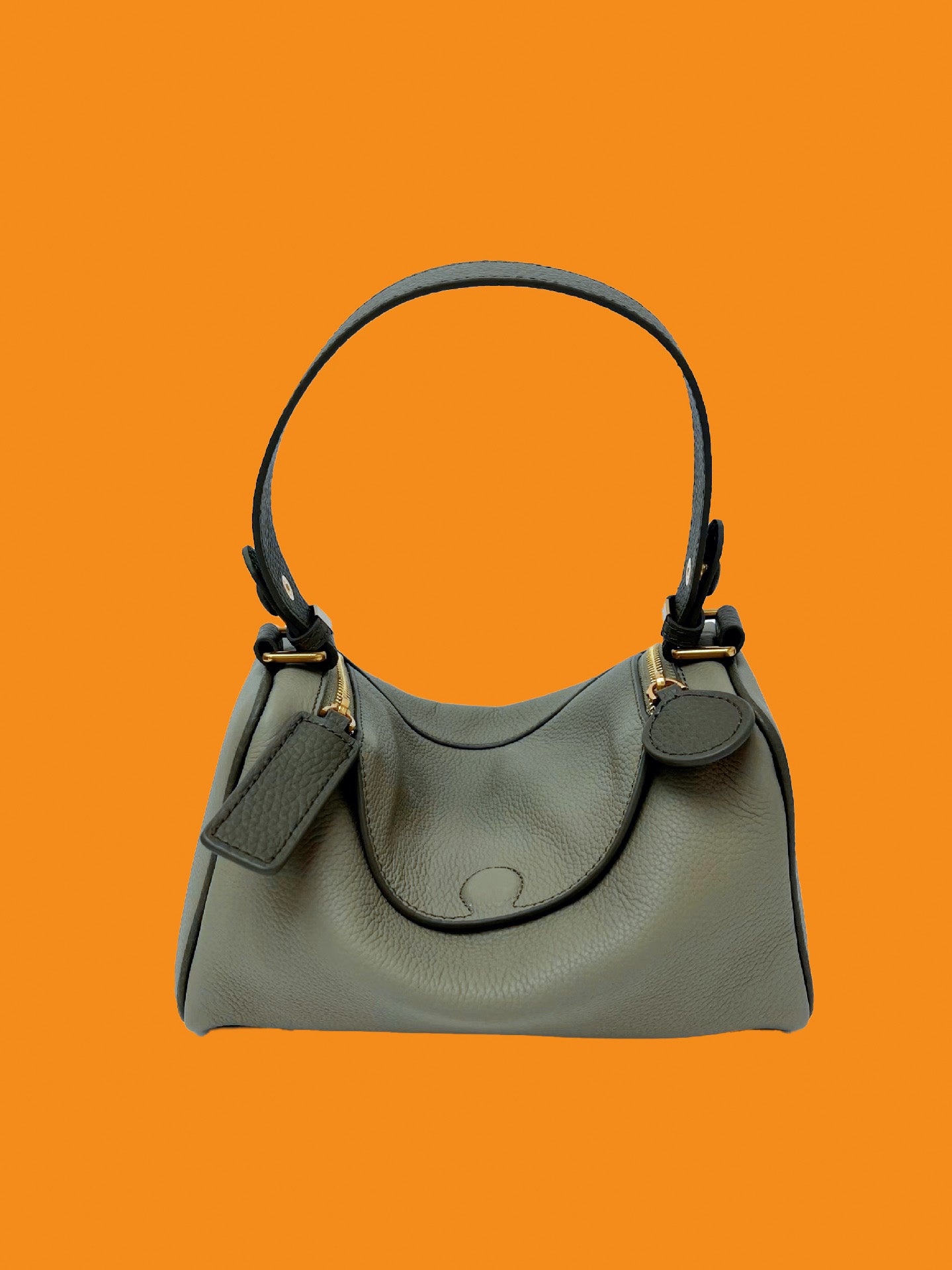 Gray handbag with black handle on an orange background