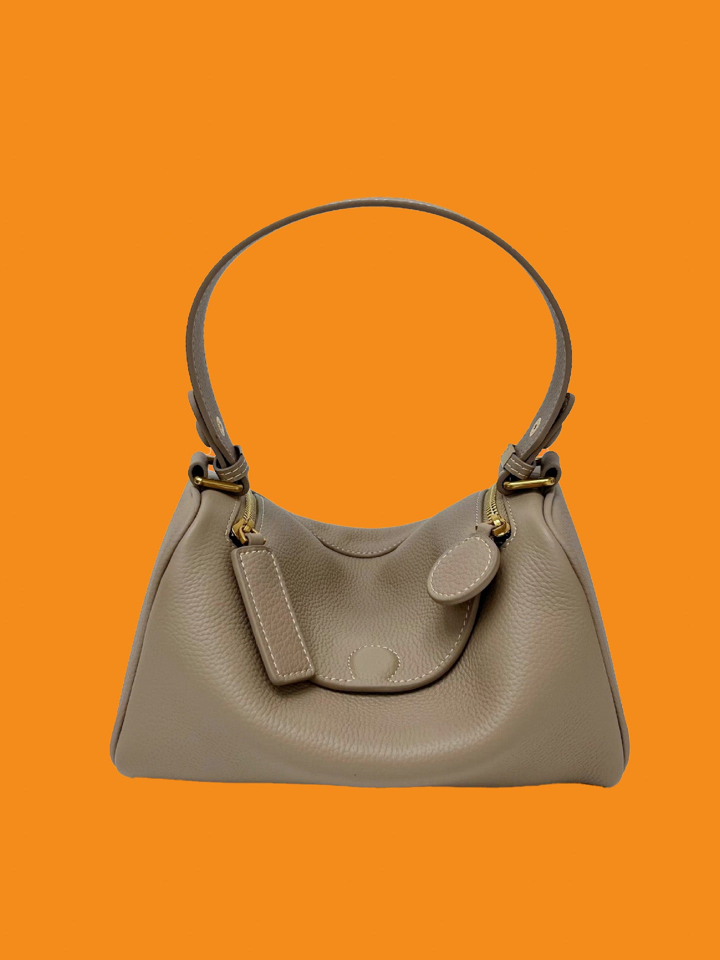 Gray handbag with gold accents on an orange background