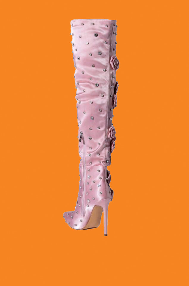 Pink knee-high boot with embellishments on an orange background