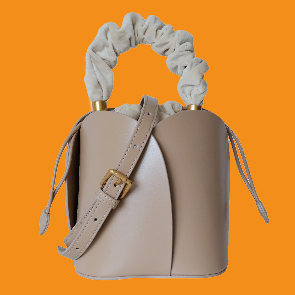 Beige handbag with decorative handles on an orange background