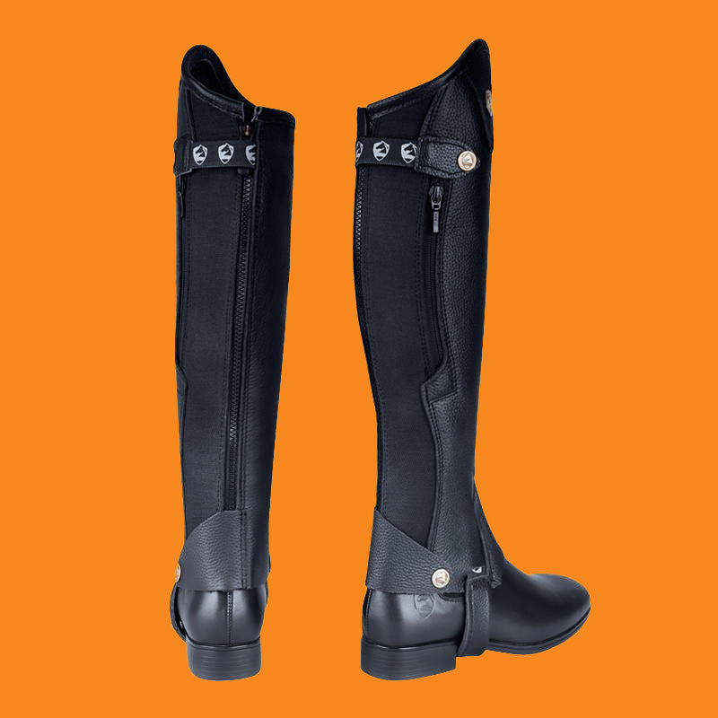 Black riding boots with zippers on an orange background
