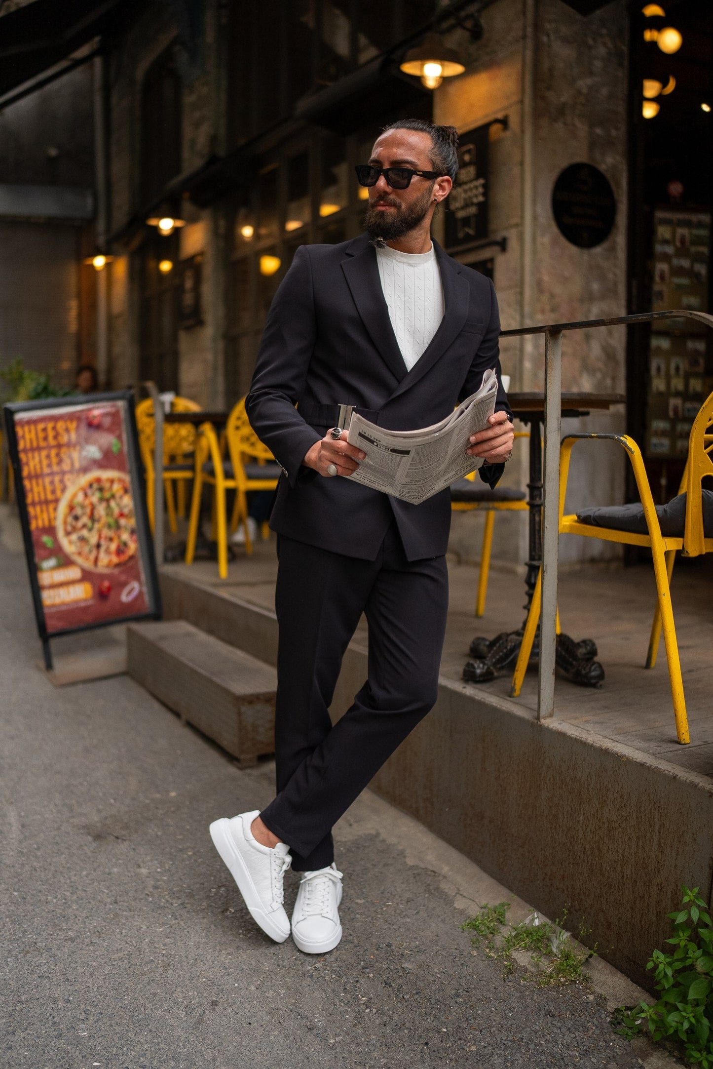 Man in a suit holding a newspaper on a city street