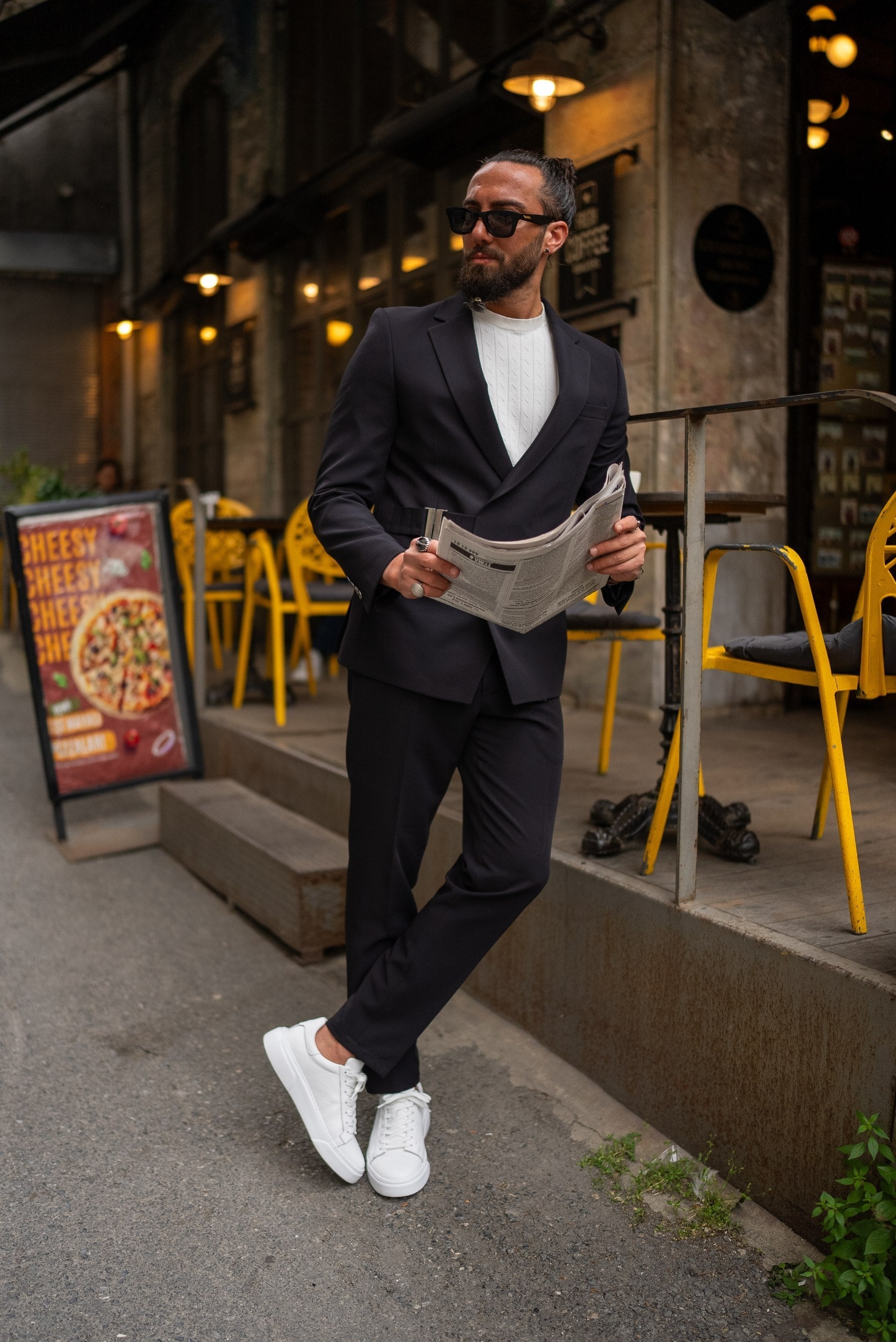 Man in a suit holding a newspaper on a city street