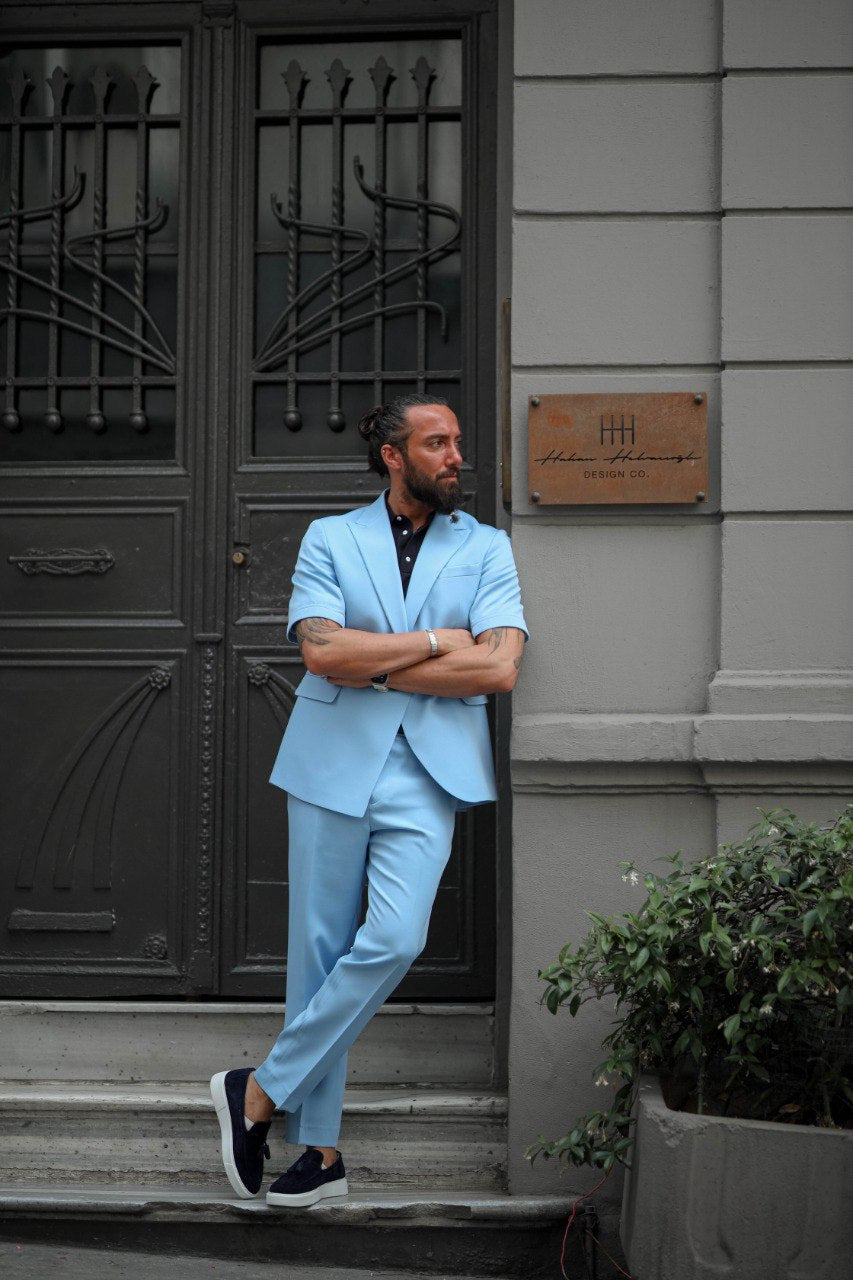 Man in a light blue suit standing on steps in front of a building entrance.