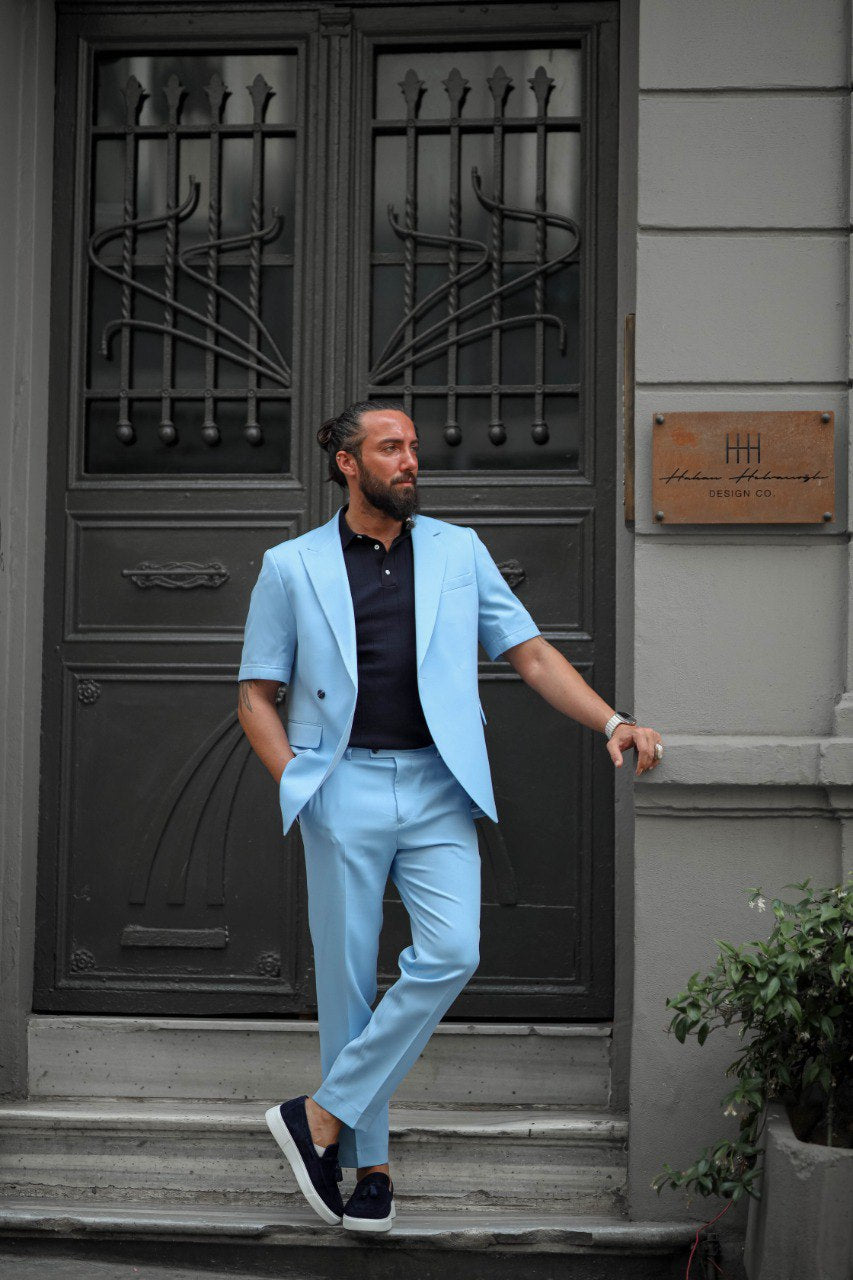 Man in light blue suit standing on steps in front of a building entrance.
