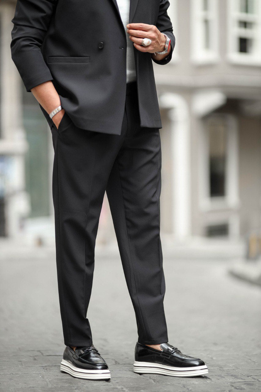 Person wearing a black suit with white sneakers on a blurred street background