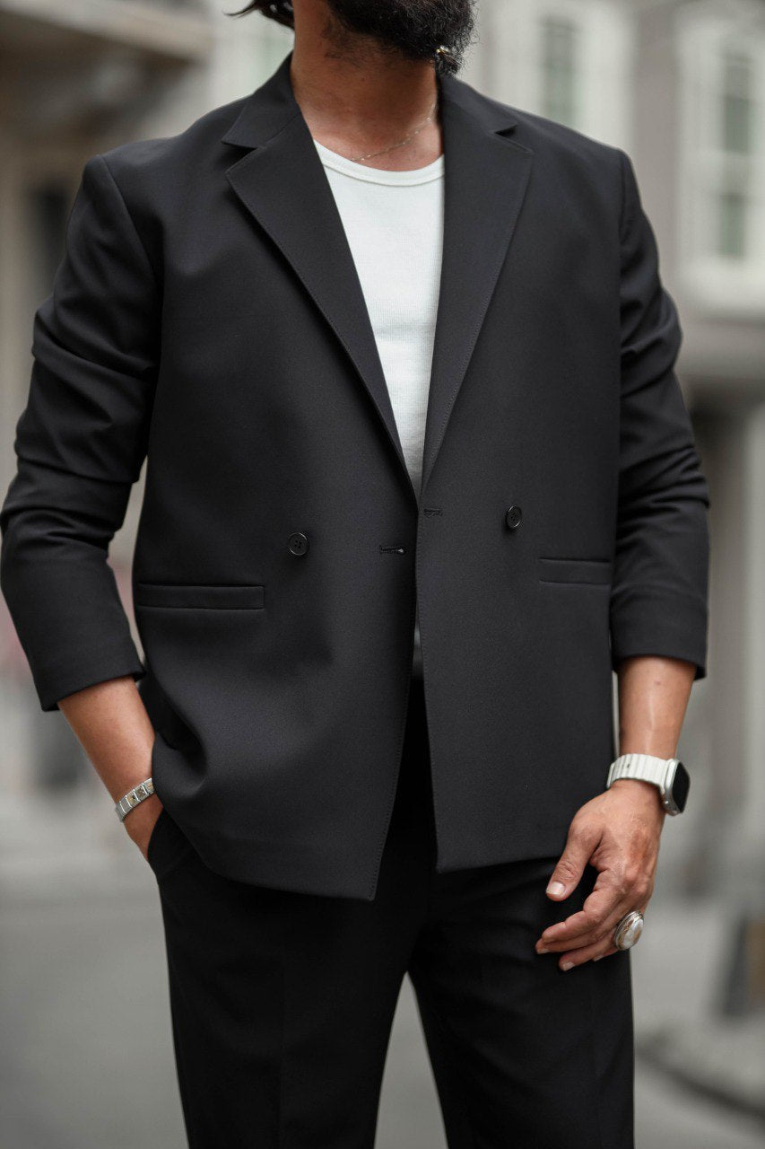 Person wearing a black suit jacket over a white shirt with a blurred background