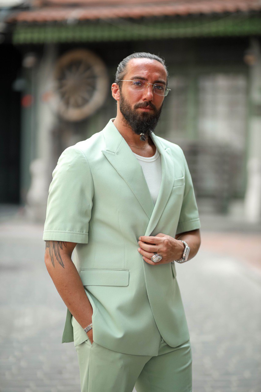 Man wearing a light green suit with a blurred background