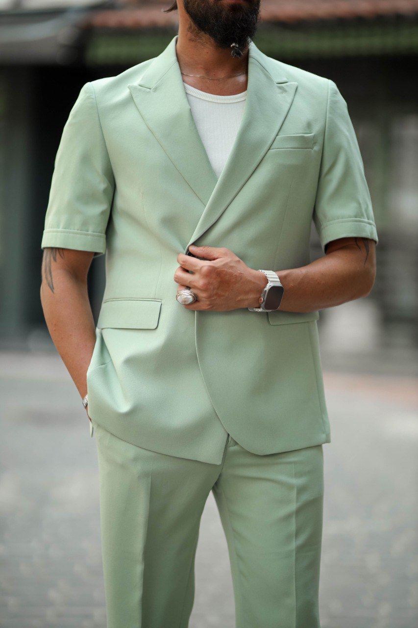 Man wearing a light green suit with a blurred background