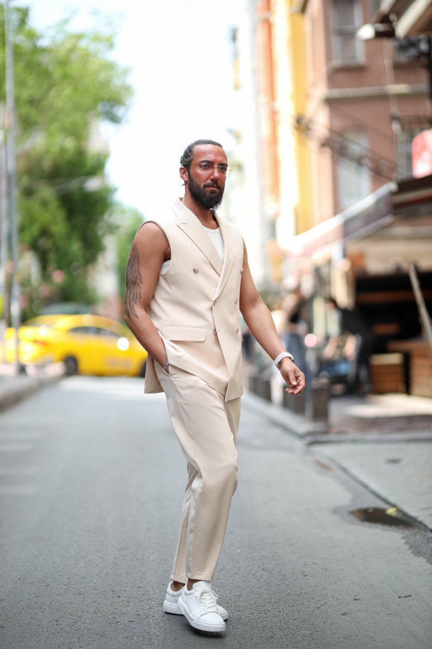 Man in a beige vest and pants walking on a city street.