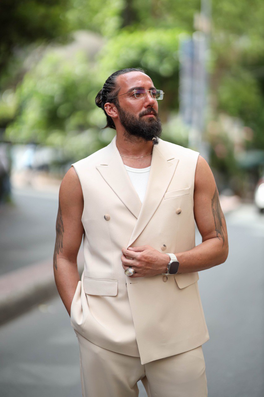 Man wearing a beige suit vest and pants on a street with blurred background